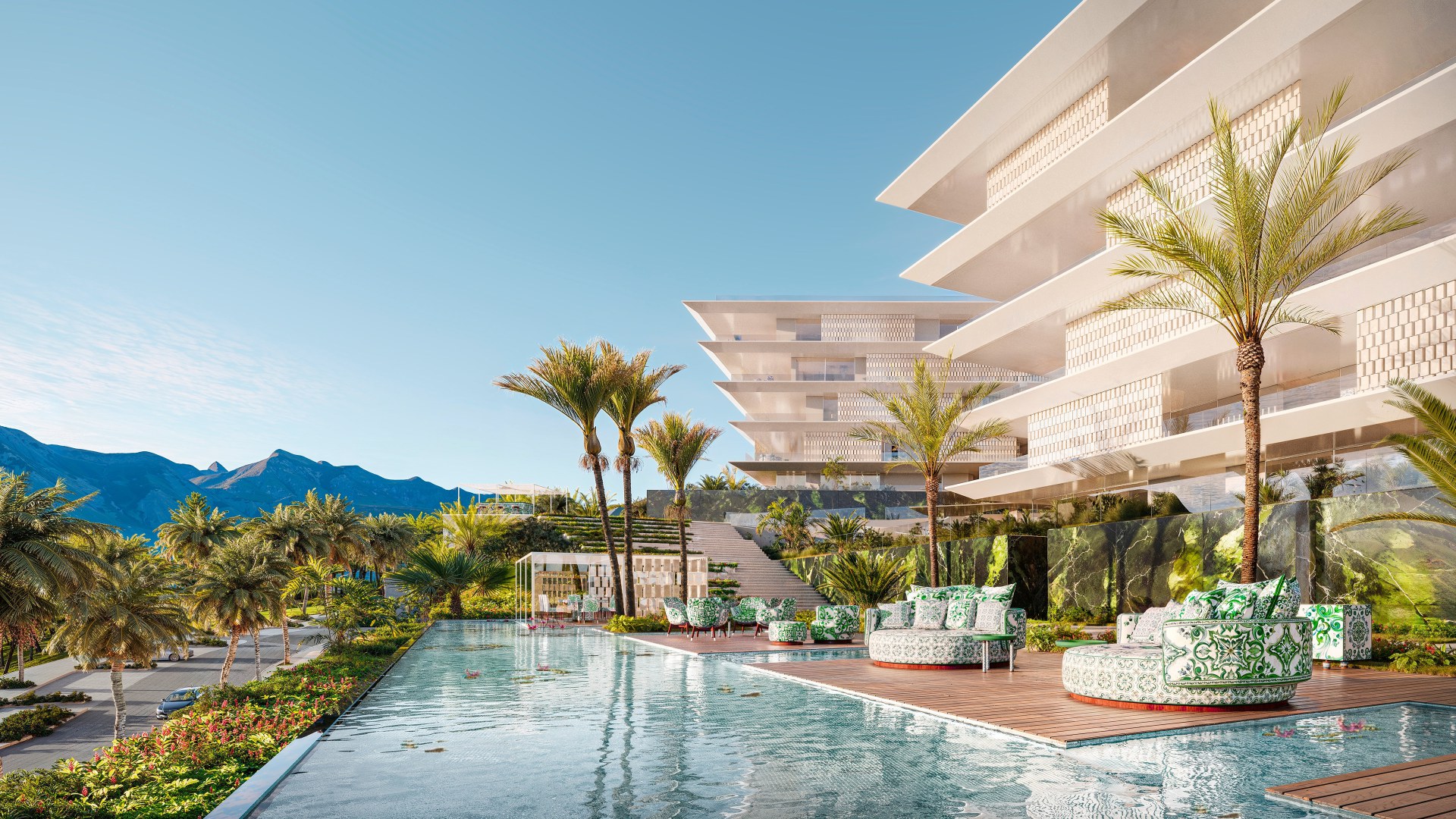 A cabana deck at Design Hills: maiolica sofas under the pergola, the pool and palms beyond, the residences and Sierra Blanca behind.