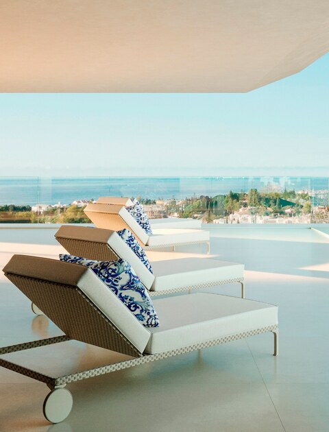 Two sun loungers with maiolica cushions facing the sea.